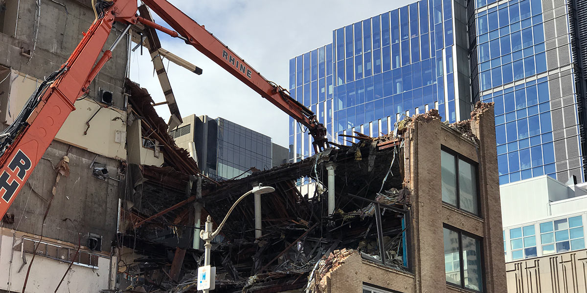 machine rips down building wall