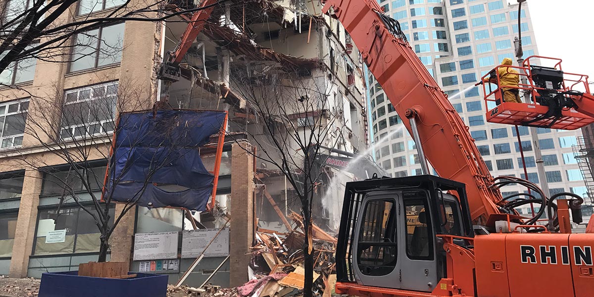 workers spray a building demolition with a fire hose